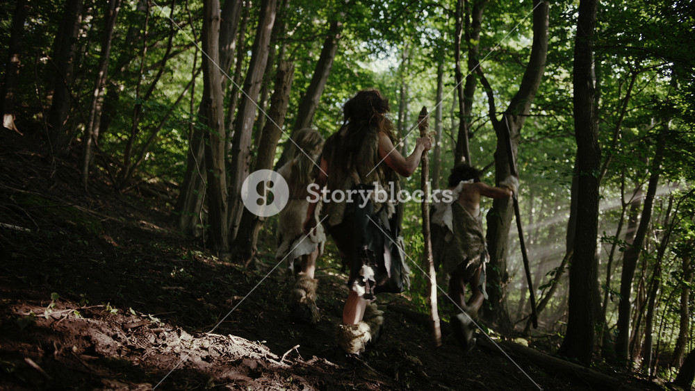 Tribe of Hunter-Gatherers Wearing Animal Skin Holding Stone Tipped Tools, Explore Prehistoric Forest in a Hunt for Animal Prey. Neanderthal Family Hunting in the Jungle or Migrating. Following View
