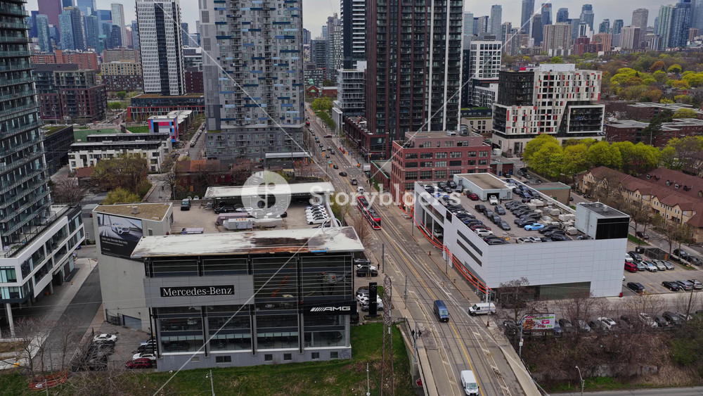 Urban landscape showing Toronto skyline with iconic red streetcar moving on street and modern apartment building next to Mercedes Benz