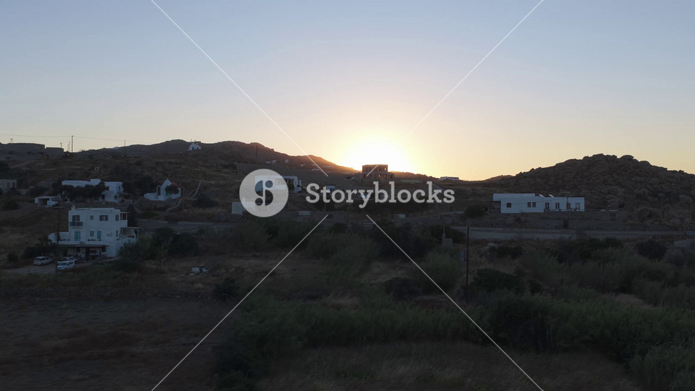 Golden sunrise over traditional Cycladic on hills of Mykonos, Greece, radiant sunbeam creating lens flare and illuminating tranquil morning