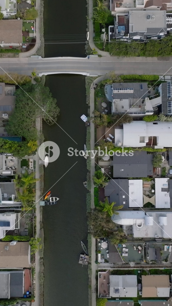 High angle view of water canals in Venice residential urban borough. Tilt up reveal of surrounding town development. Los Angeles, California