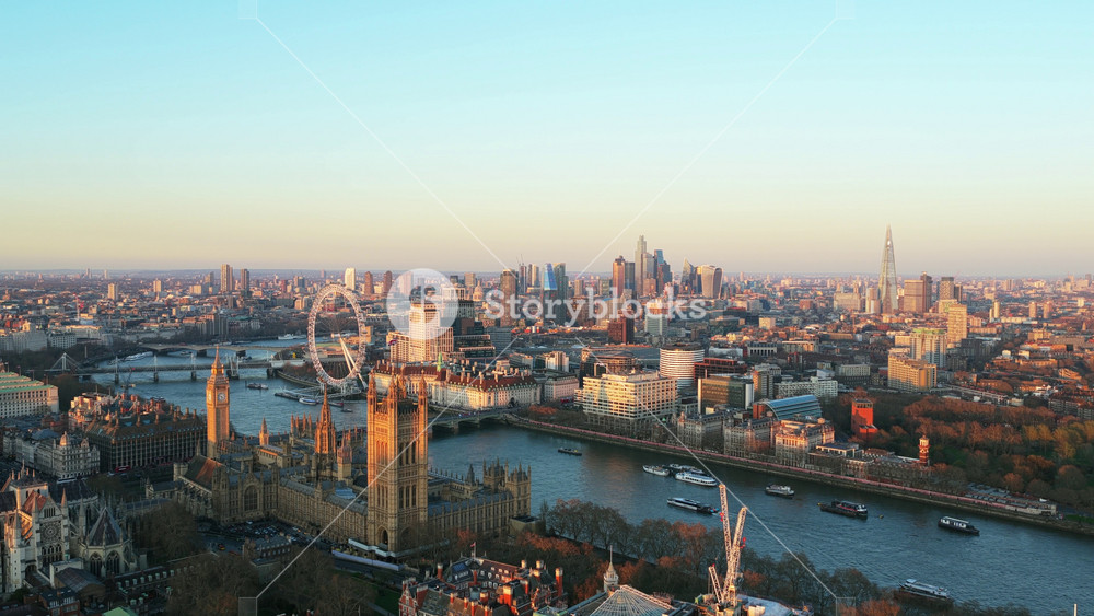 Golden hour flight showing London Eye and Palace of Westminster along River Thames with City of London financial district in the background