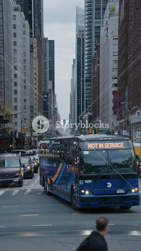 Busy city street in Manhattan, congested traffic with yellow taxis and a city bus, framed by towering skyscrapers and modern buildings in