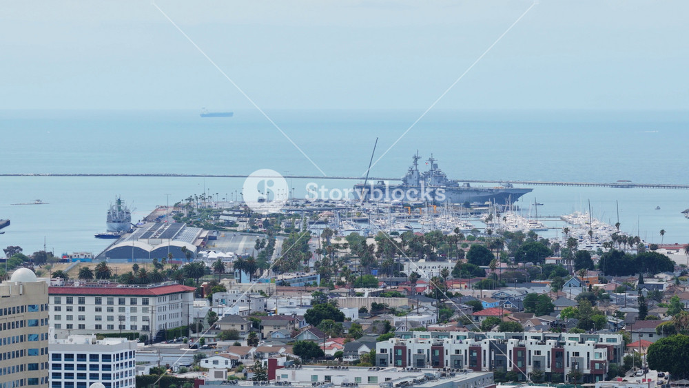 Port of Los Angeles cityscape featuring moored military vessels including battleship and aircraft carrier near San Pedro peninsula