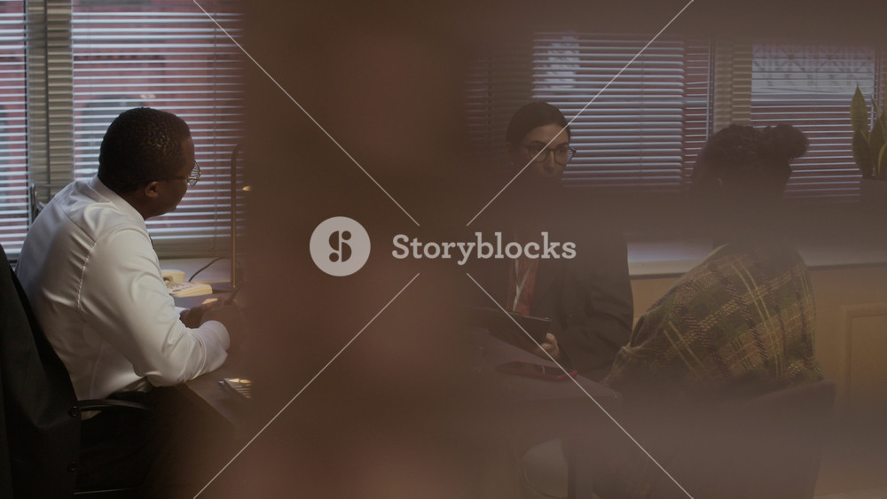 Medium long shot of black woman listening to female psychologist while having meeting with principal in modern school office