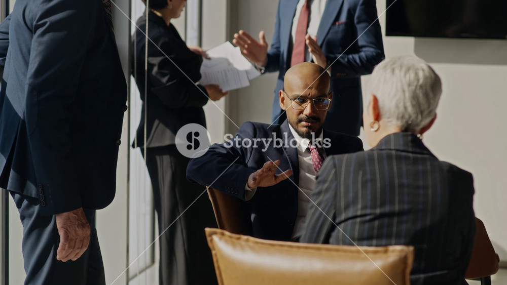 Handheld shot of diverse executives, including Caucasian and Indian colleagues, discussing corporate strategy during oil industry meeting. Video is ideal for business presentations