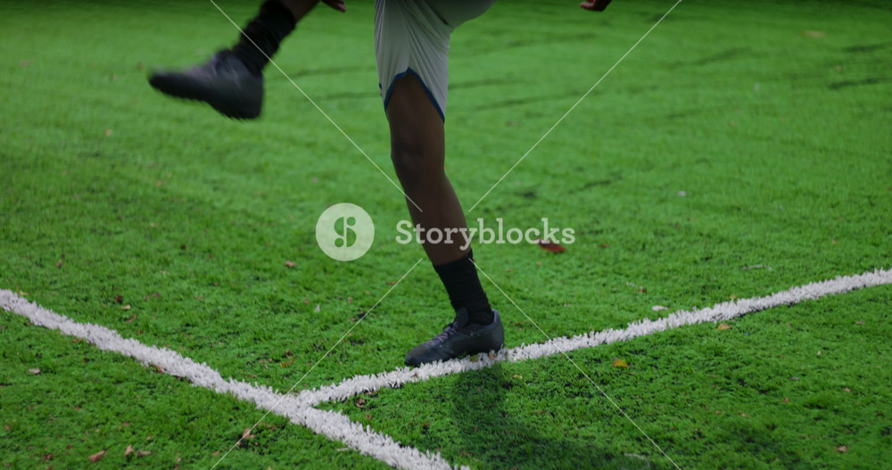 Close up of Brazilian man of African descent juggling soccer ball on green field demonstrating balance, agility and confidence during solo training practice outdoors