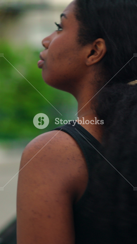 Young African American Woman walking through neighborhood streets from behind showcasing independence freedom and relaxed confidence in a peaceful urban setting