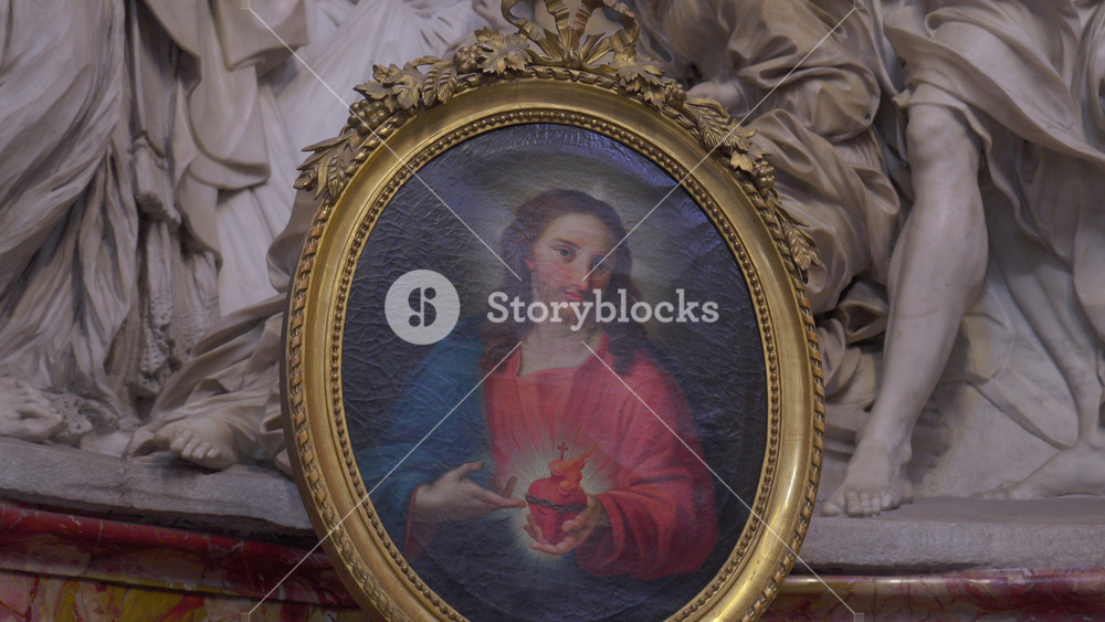 Rome, ITALY, JULY 30th, 2025 - Close-up of framed painting of Sacred Heart of Jesus set before marble relief sculptures inside basilica