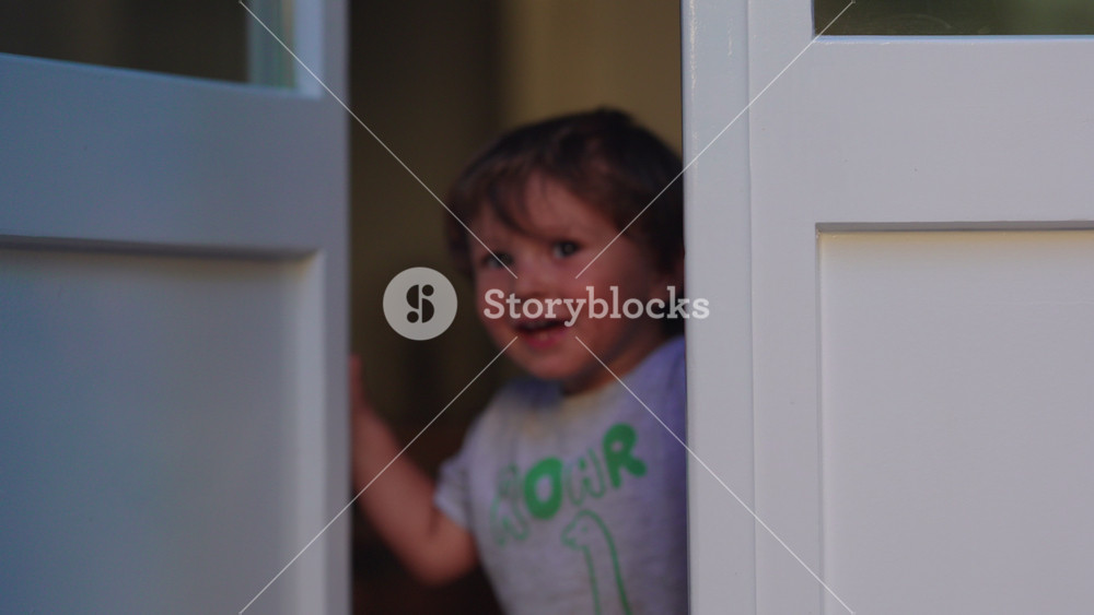 Happy toddler opening and closing door at home, smiling with excitement while greeting loved one, expressing joy, anticipation, playful childhood, family connection