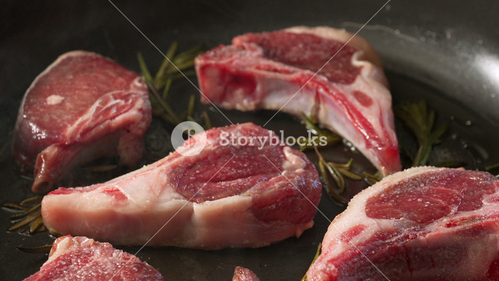 Raw Lamb Chops Seasoned And Arranged On Pan With Sprigs Of Rosemary Before Cooking Showing Detailed Texture And Marbling Of Fresh Uncooked Meat