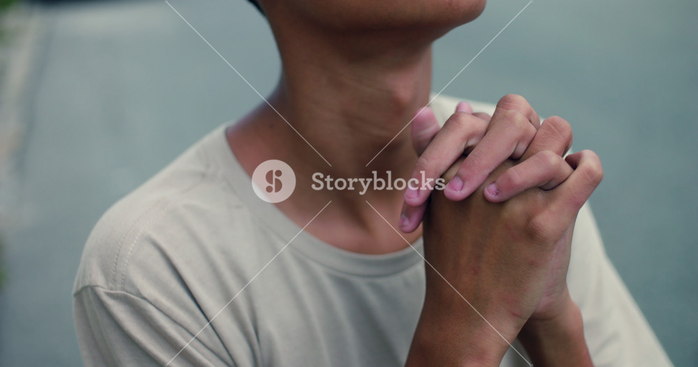 Hispanic teenage boy of African descent praying with clasped hands looking up, deep in faith and contemplation, outdoors, spiritual devotion, hope, emotional moment