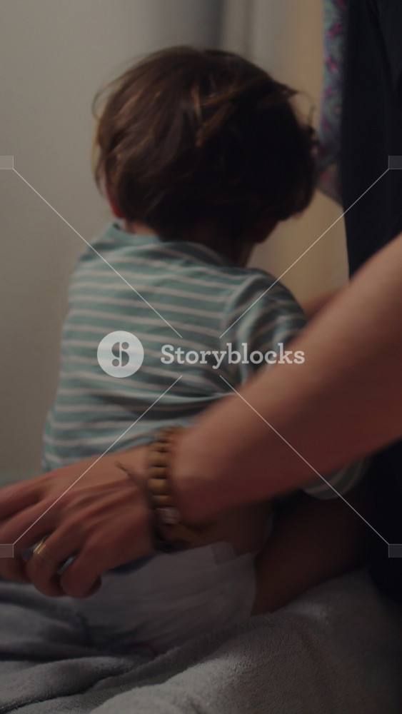Mother dressing toddler on bed at home, daily childcare routine and caregiving moment, nurturing parenting and gentle support in calm indoor family environment