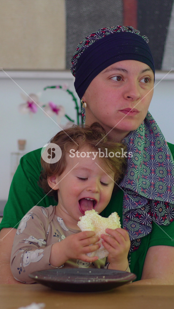 Mother holding toddler close during family mealtime at home, heartwarming parenting moment highlighting attachment, comfort, emotional security and nurturing family bonds