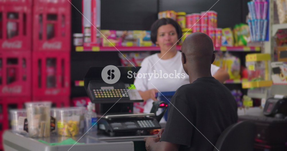 African American supermarket worker assisting Latina customer with groceries at checkout, casual grocery store scene indoors with colorful retail shelves in background