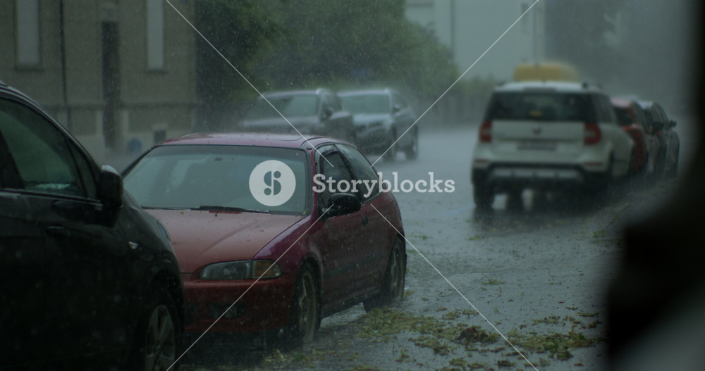 Red Compact Car Sits In Long Row Of Parked Vehicles During Torrential Rainfall In Residential Neighborhood With Flooded Street And Poor Visibility
