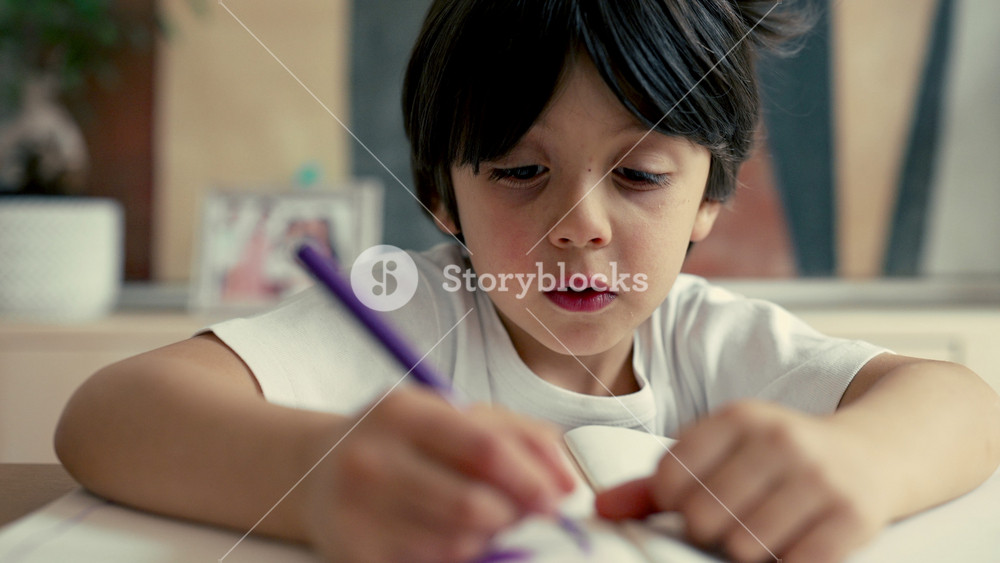 Child drawing with a purple pen, hands and face visible, focusing on creating a detailed piece of art in a cozy home environment, showcasing the process of childhood artistic expression