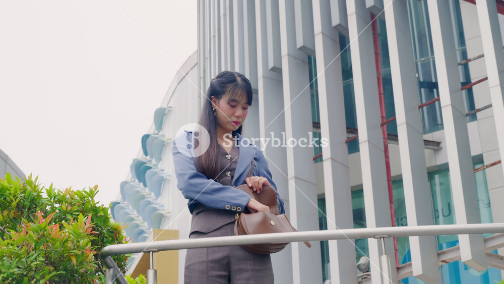 Young business businesswoman talks on phone, checks wrist time, walking outdoor modern office buildings, urban city