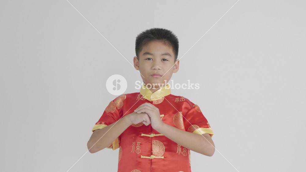 Happy Chinese New Year Smiling Asian boy in a traditional red cheongsam qipao dress makes a congratulatory gesture