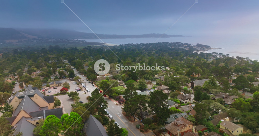 Dramatic dark stormy skies over the beautiful marine city of Carmel, California, USA. Drone flying low over the tree tops.