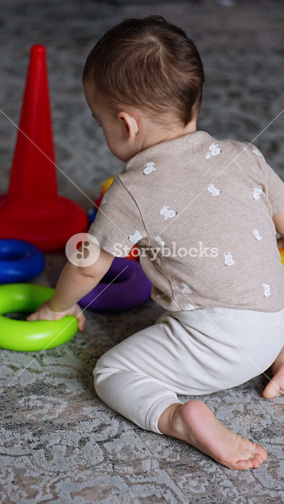 Sweet little baby boy playing with toys on the floor. Lovely toddler assembling pyramid and then crawls up the stairs. Vertical video