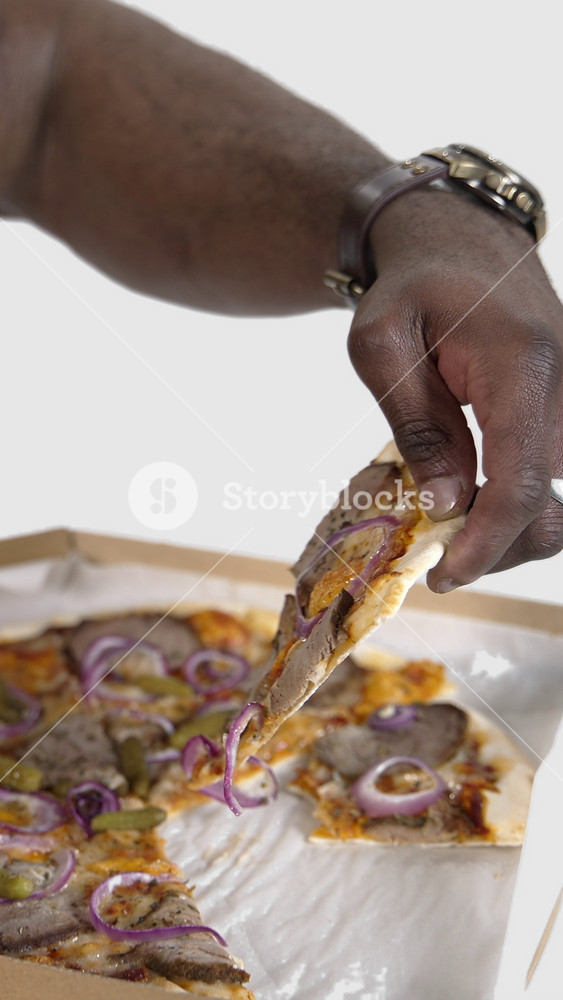 Delicious pizza in black man's hands. African man holds a box with delivered pizza and trying to eat some slice. Unhealthy food. Close-up. Slow motion. Vertical video