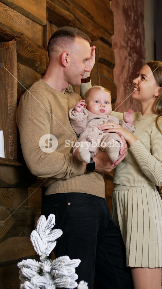 Man holding a baby stands leaning to the wall. Loving woman strokes her husband's head and touches her baby tenderly. Vertical video