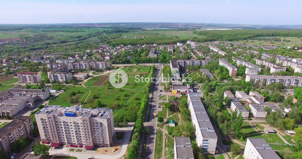 Provincial city panorama shot on sunny day in summer. Residential neighborhoods and green zones from aerial perspective.