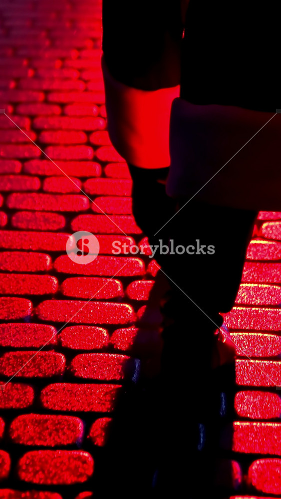 Santa Claus walk on pavement. Legs of Father Frost at Christmas outdoors. Boots of Santa walking on a pavement at dark. Red lighting. Back view. Vertical video