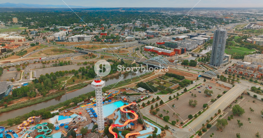Flying above Elitch Gardens amusement park and South Platte River in Denver, Colorado, USA. Panorama of big lively city with busy traffic. Top view.