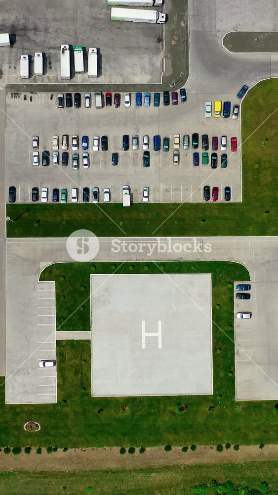 Industrial territory on green field. Flight over the field and car parkings of a modern factory. Cars and trucks on parking spaces. Aerial view. Vertical video