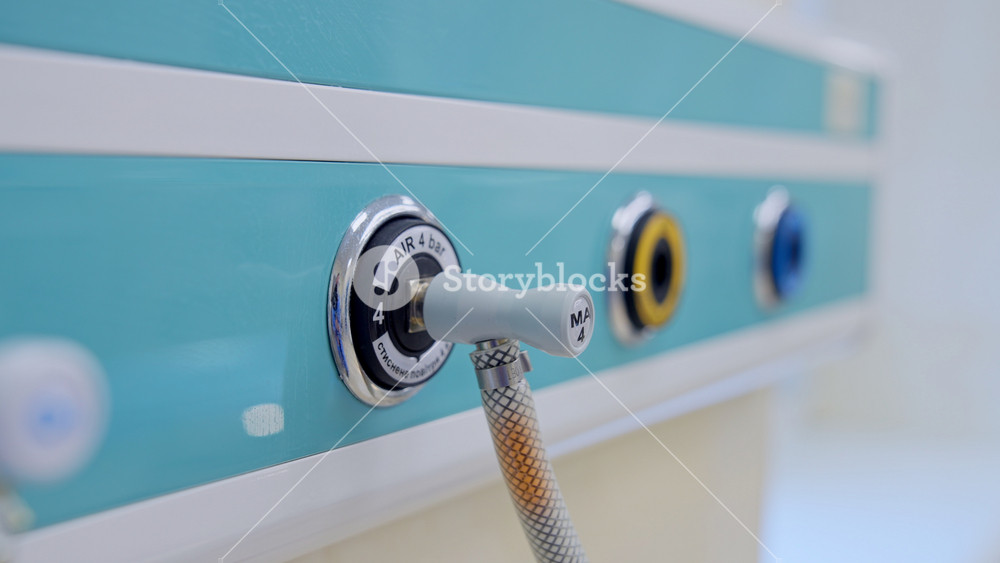 Air supplier connected to the apparatus through the tube. Slots in the panel on the wall of modern surgical theatre. Close up.