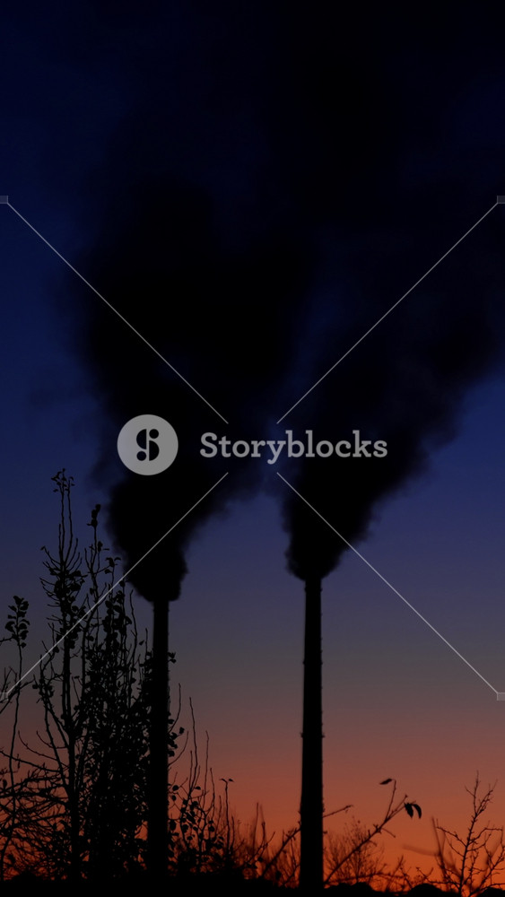 Amazing blue and pink sky in the dusk. Silhouettes of plant pipes produce smoke emitting it into the air. Vertical video