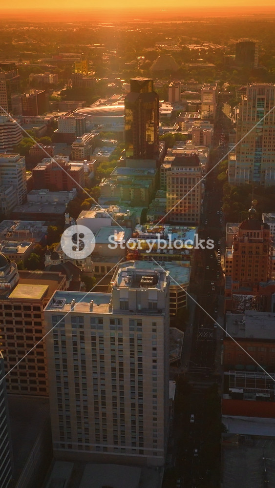 Beautiful architecture of modern American city in the rays of setting sun. Sacramento panorama at the backdrop of orange skies. Top view. Vertical video