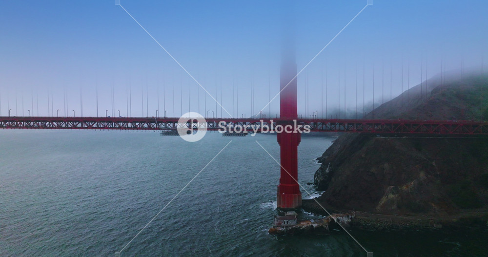 Well recognized supports of beautiful Golden Gate Bridge near the rock. Cars going by the bridge. Amazing Landmark of San Francisco, California, USA.