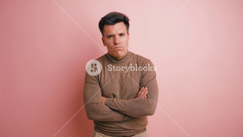 Disappointed adult man with folded arms expressing negative emotions. The serious person is looking at the camera with a displeased facial