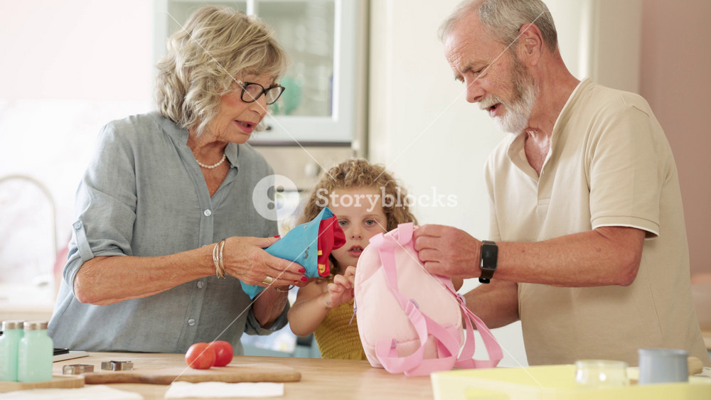 Senior grandparents helping their cute granddaughter pack her backpack for school. Happy family preparing for the first day of school