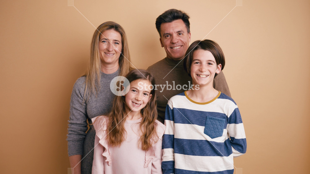 Happy family with mother, father, son, and daughter smiling and posing for a portrait. Parents with their children standing together