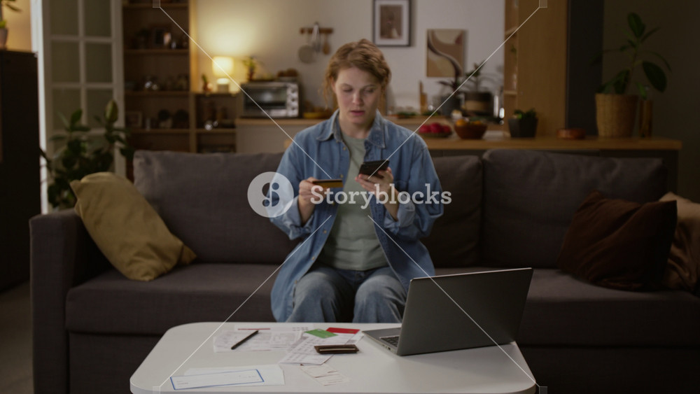 Medium zoom-in shot of deceived young Caucasian woman with credit card checking bank alerts on smartphone, then crying at having money stolen by scammers, after revealing personal details and password