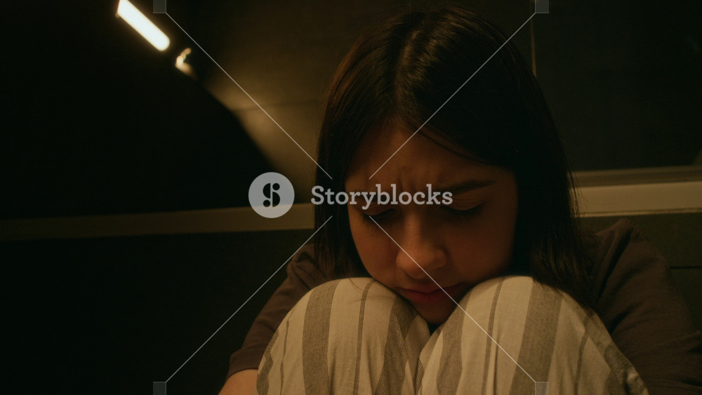 Close-up portrait of depressed, desolate teenage Caucasian girl crouching on floor alone in bathroom, looking at camera, suffering from bullying, harassment or relationship breakup