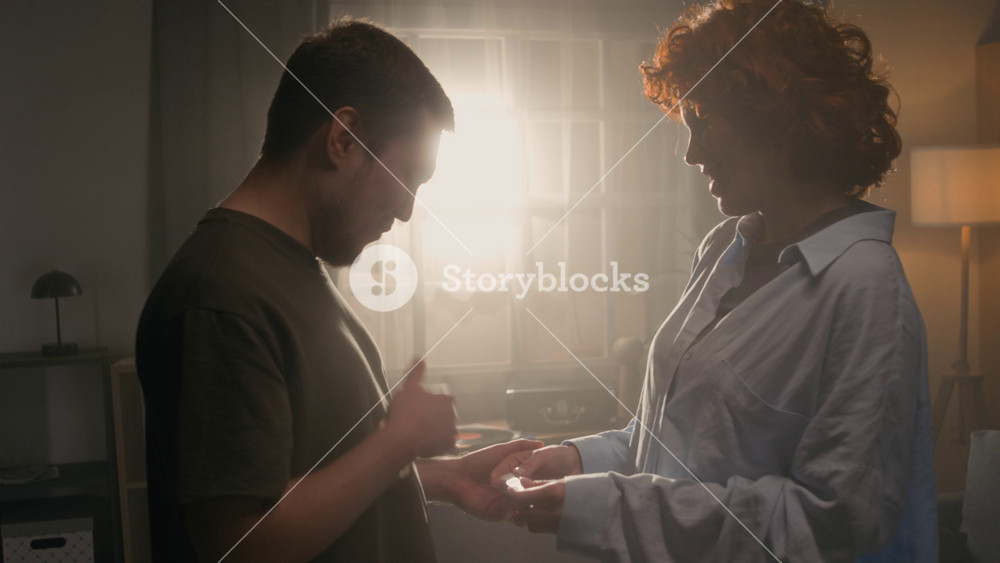 Cinematic side view shot of young woman showing positive pregnancy test to happy husband and embracing happily jumping up backlit by soft sunlight, copy space