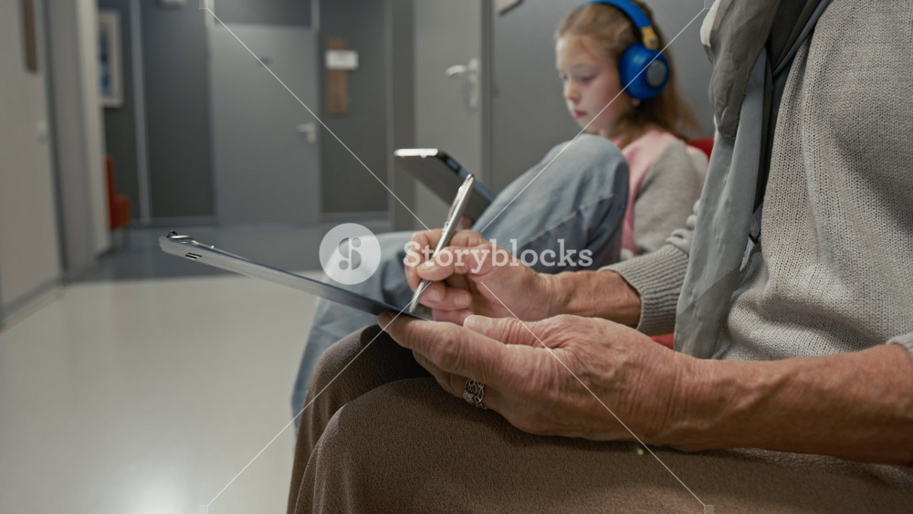 Close up shot of senior woman writing on clipboard and filling in patients form while waiting for doctors appointment in clinic waiting room focus flowing from face to hands, copy space
