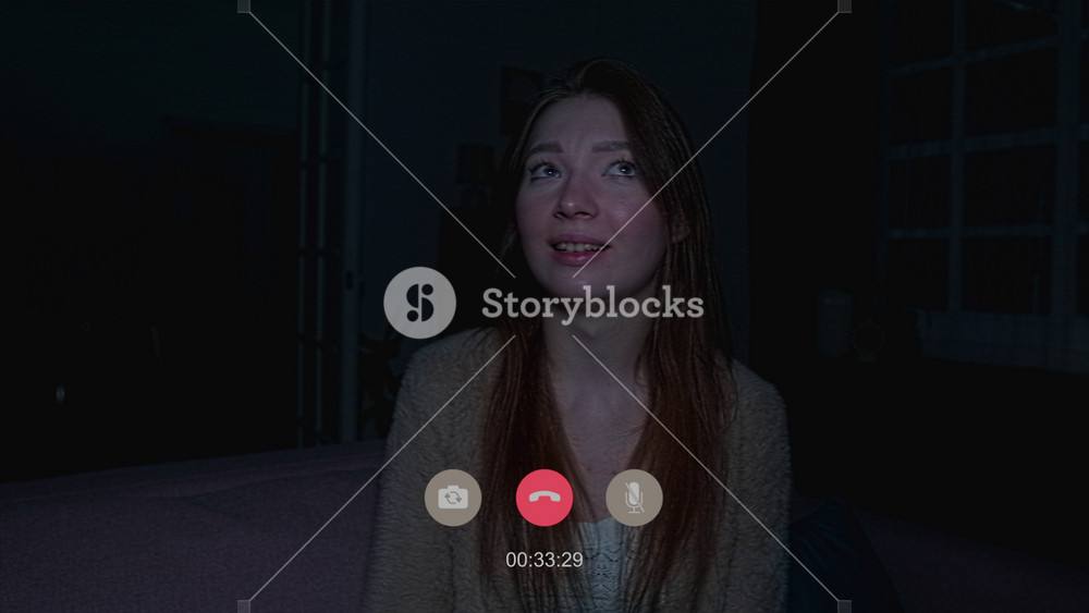 Close up of carefree woman sitting in front of camera chatting on video call while lightning flashes outside then power outage causes lamps to go dark and figure of intruder appears in hallway