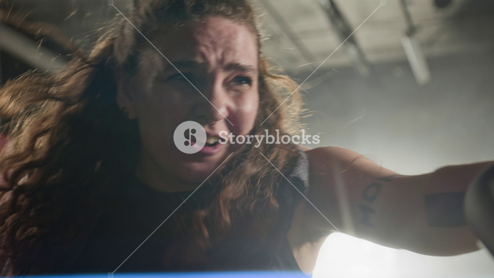 Young Caucasian woman exercising intensely on air bike in gym, sweating and grimacing with effort. Ideal for fitness brand commercials and motivational gym advertisements