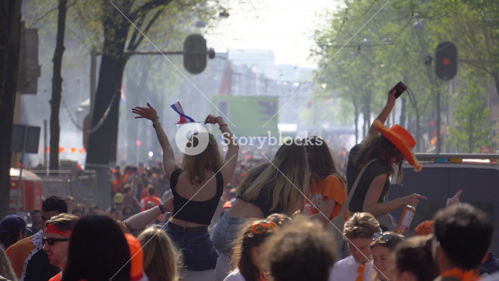 AMSTERDAM, NETHERLANDS - 26. 04. 2025: Festive Girls are Dancing in Crowd of People Wearing Orange, Kings Day in Amsterdam