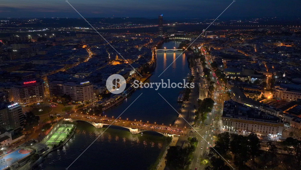 Guadalquivir river in Seville Old town at Night, Aerial Triana Bridge, City illumination. Sevilla, Andalusia, Spain.