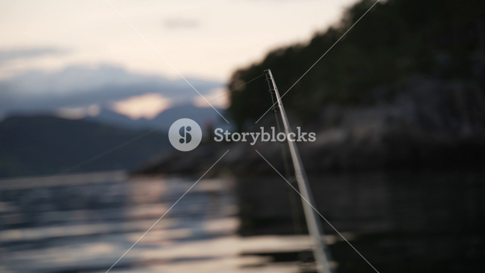 Leisure Fishing in Fjord. Man is fishing with Fishing pole rod spinning in Norway. Scandinavian Fjords Boat Fisherman.