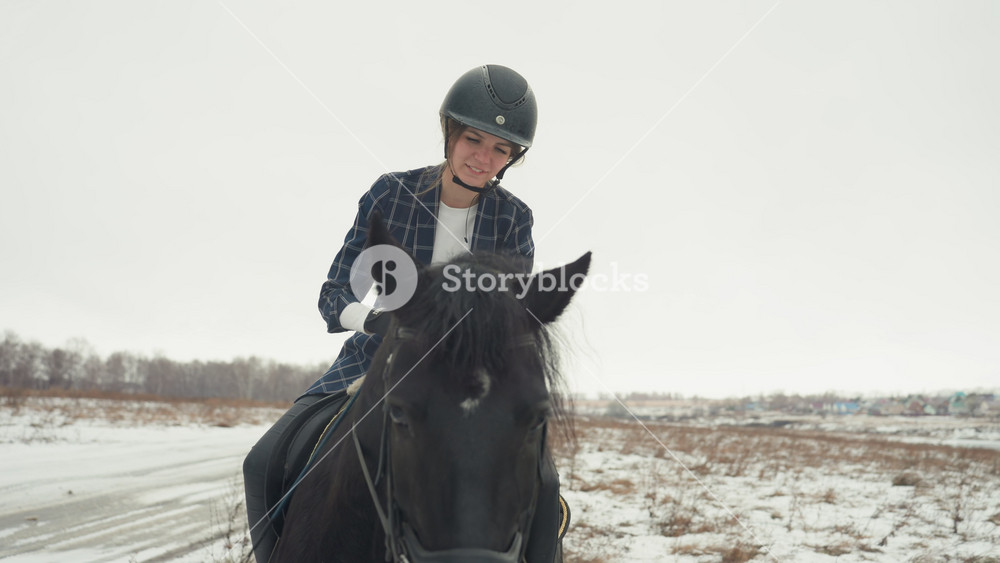 Peaceful woman atop horse in snowy field. Tranquil scene of woman riding horse through winter landscape. Gentle woman on black horse