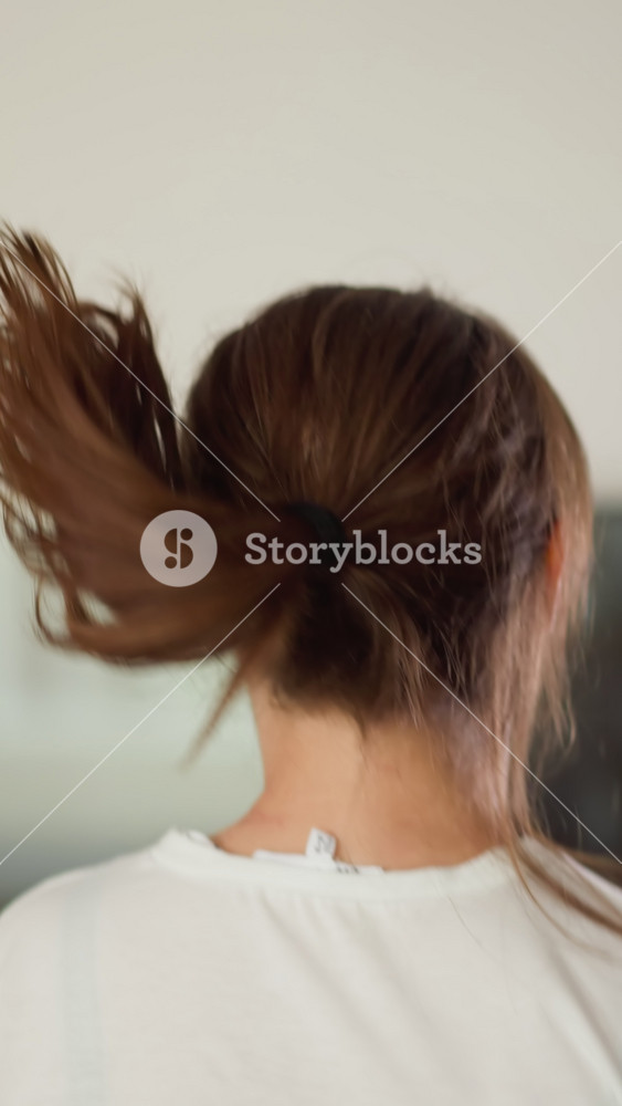Running woman pulls down hair at home. Sportive lady in white t-shirt jogs with waving loose hair in domestic gym. Exercising for wellbeing