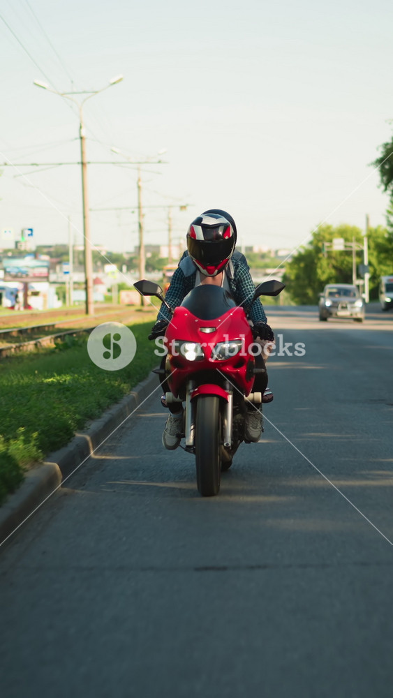 Two ladies ride a power bike wearing helmets, traveling close to railway tracks with electric poles and signposts in the background