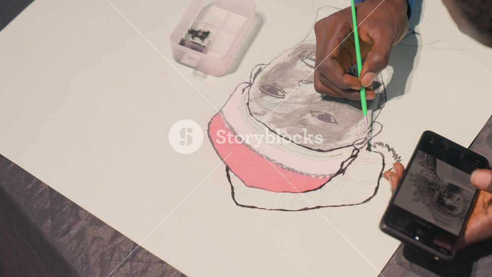 Black portrait layering artist applying wash gentle gray tones sculpt cheek and brow, phone reference nearby, water tray and green brush